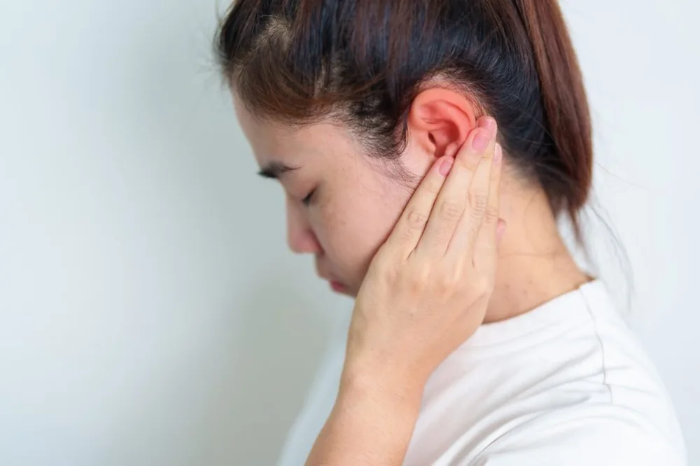 Young person holding their ear in pain