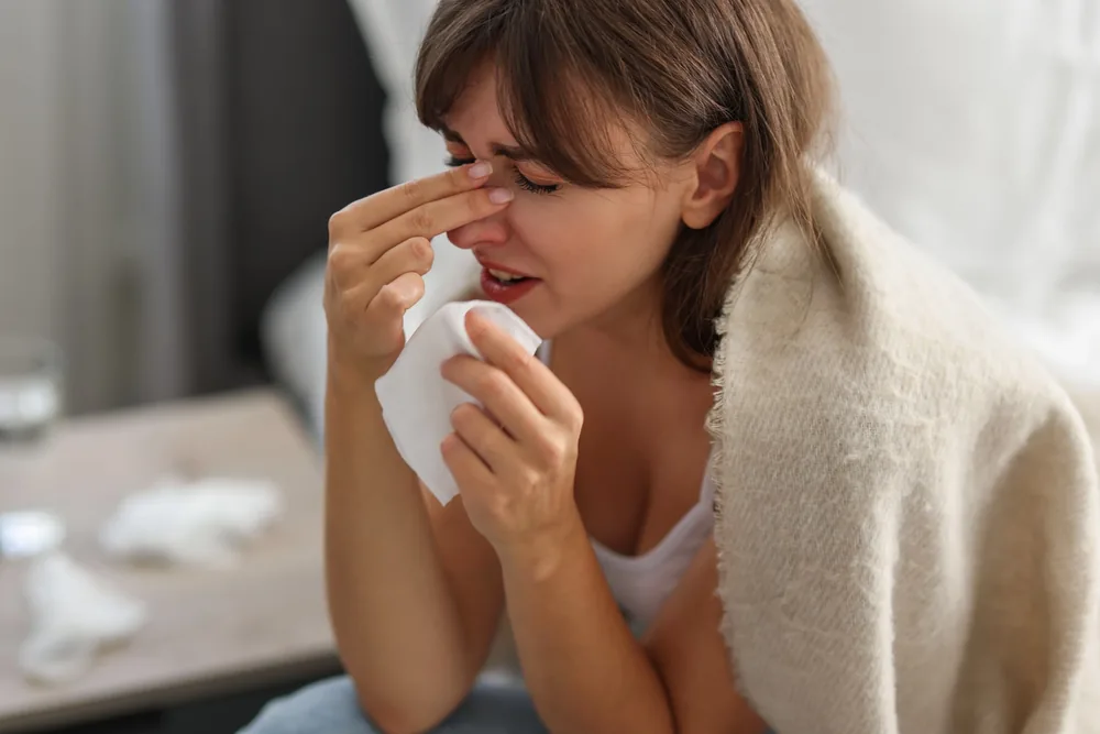 Woman holding a tissue with sinus pain