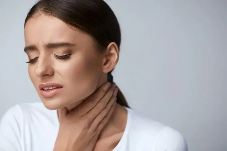 Woman holding her throat in discomfort