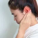 Person holding the side of their head with ear pain